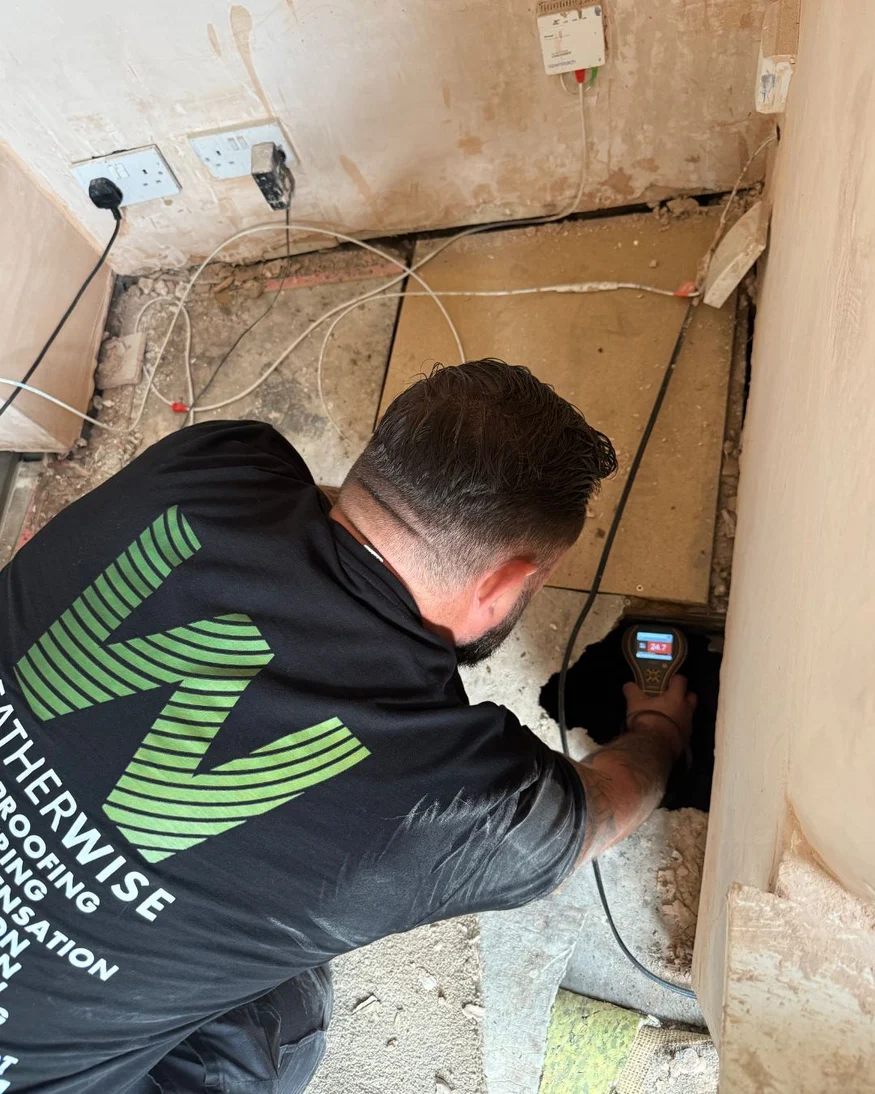 Weather Wise surveyor taking a moisture reading at floor level during a damp investigation
